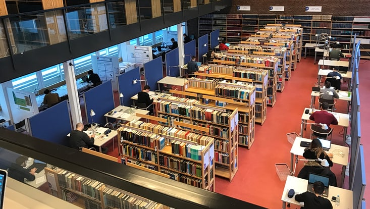 Blick von oben in die Bibliothek, Studierende lernen an Arbeitsplätzen