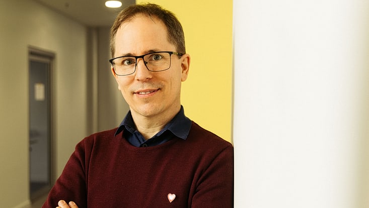 Portait of Grischa Perino, a white male, short hair, wearing glasses and a dark red pullover