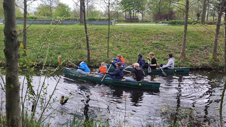 Gruppe junger Leute in zwei Kanus auf einem Bach