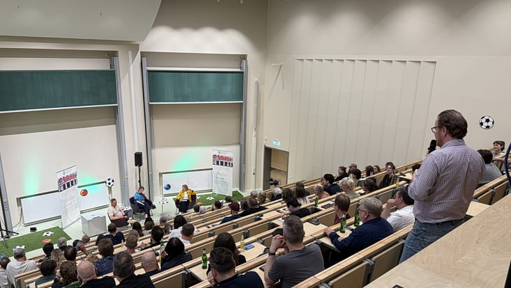 Zu sehen ist ein Hörsaal in dem viele Menschen sietzen