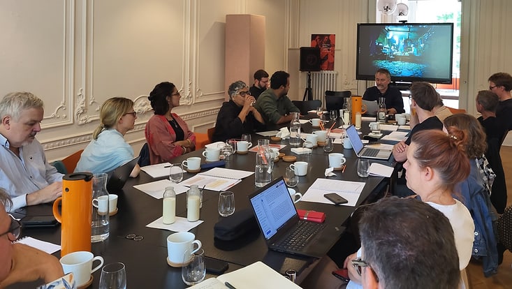 Researchers are seated around a large table during a workshop