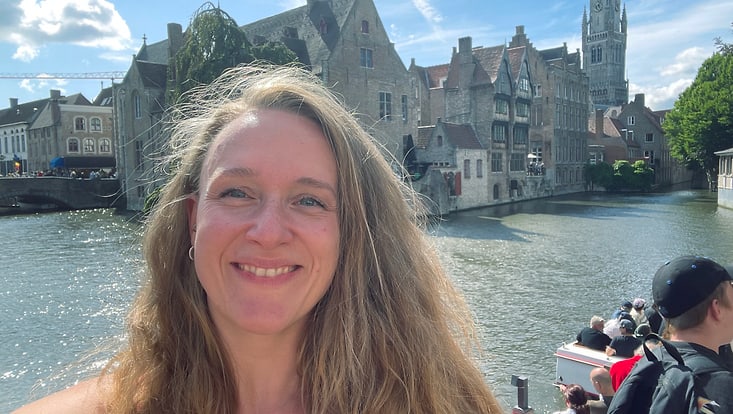 Vacation photo of Tina Niemann in Belgium on a barge with water and historic buildings in the background.