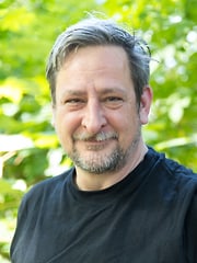 Person im Profil vor grünem Busch
