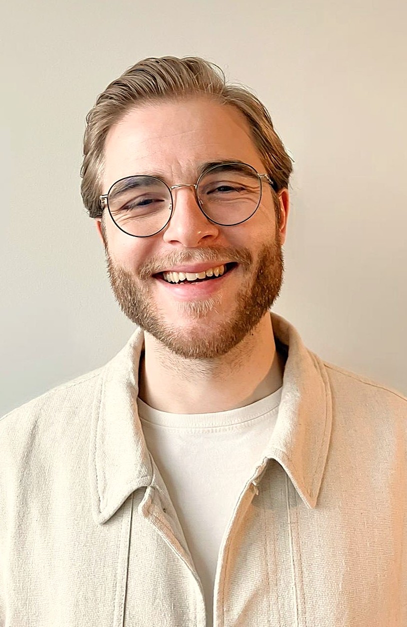 Porträtfoto eines Mannes mit kurzen Haaren und Brille vor einer hellen Wand