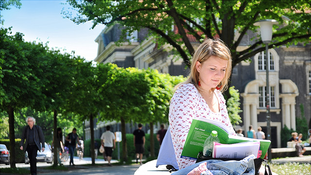 Studentin auf dem Campus, lesend.