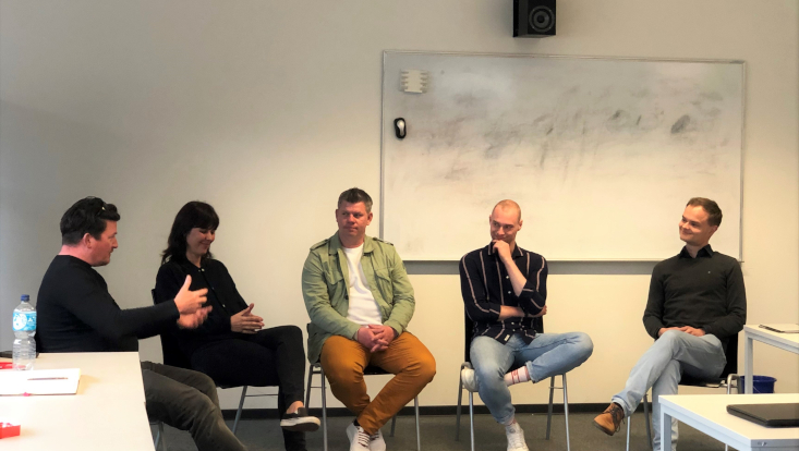 fünf personen diskutieren in einem seminarraum