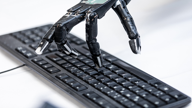 Roboter-Hand tippt auf einer Computer-Tastatur