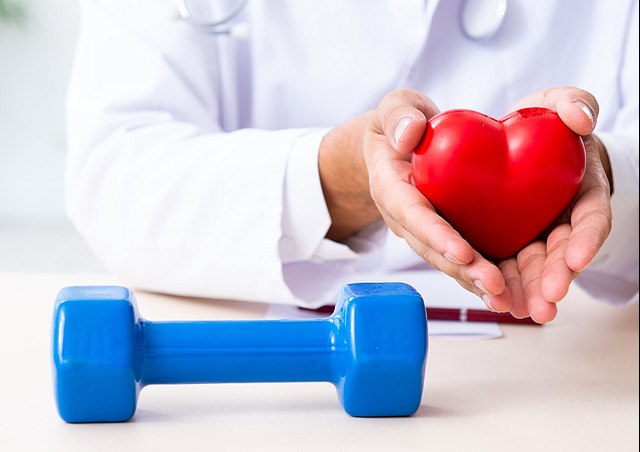 Hände eines Arztes mit einer Hantel im Vordergrund