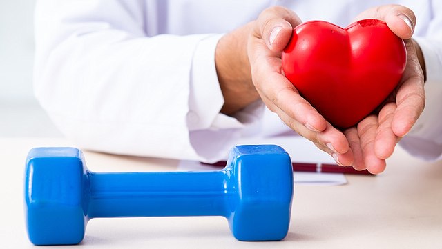 Hände eines Arztes mit einer Hantel im Vordergrund