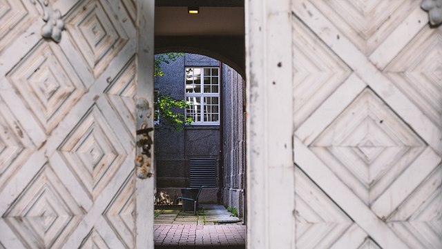 FAQ Blick durch halboffenes Tor in Hinterhof