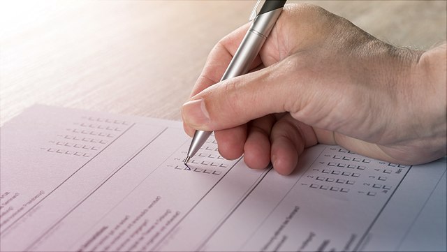 Hand mit Stift Hand mit Stift füllt einen Fragebogen aus