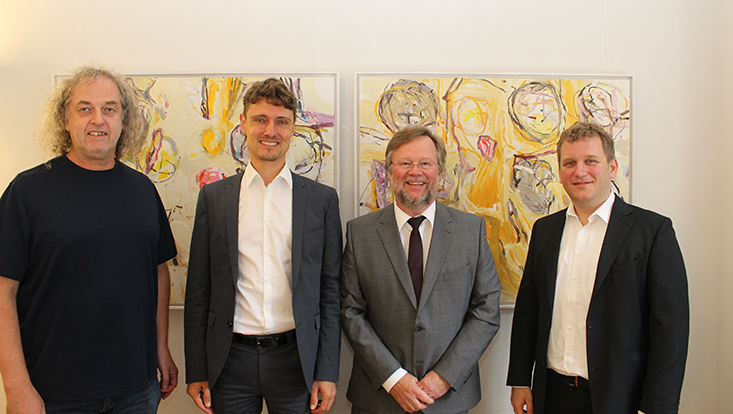 Die dekanatsmitglieder stehen nebeneinander von einer Wand mit zwei Bildern der Künstlerin Elke Wree. Von links nach rechts sind zu sehen Prodekan Prof. Stefan Voß, Dekan Prof. Schreyögg, Studiendekan Prof. Grotherr und Forschungsdekan Prof. Voigt.