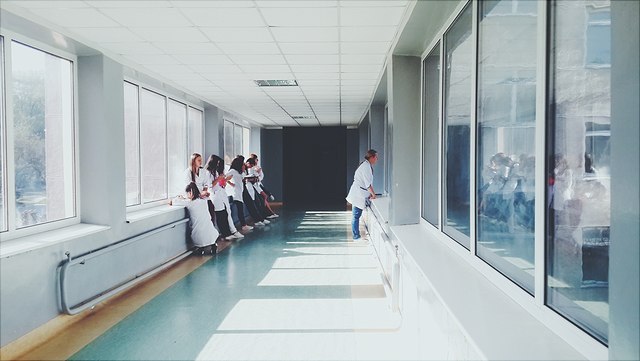 chronisch-640x361 Auf diesem Bild ist ein Korridor zu sehen, an dessen Seiten sich jeweils mehrere Ärzte an die Wände anlehnen