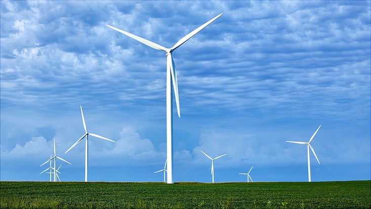 Wind turbines on green field in front of blue sky