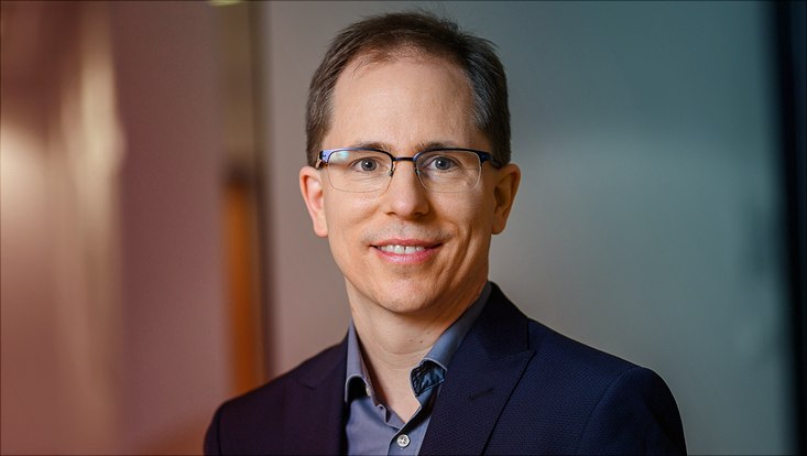 Männliche Person mit dunklem Haar, Brille und dunkelblauem Hemd
