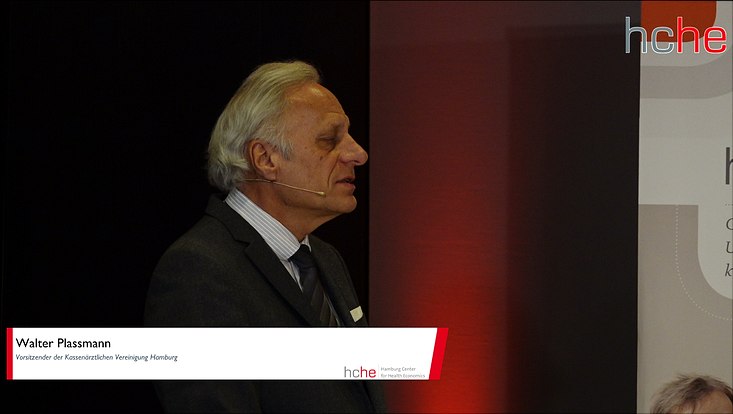 rrl-corona-bild-7-733x414 Walter Plassmann steht am Tisch und spricht. Oben rechts ist das Logo des hche eingeblendet.