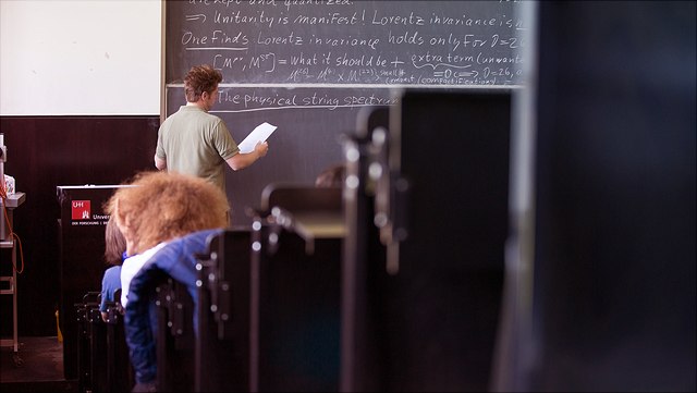Männliche Person vor Tafel im Hörsaal