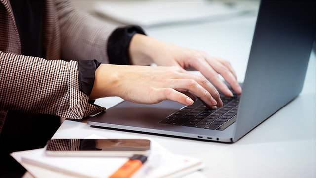 Schwarzer Laptop und Handy auf weißem Tisch.