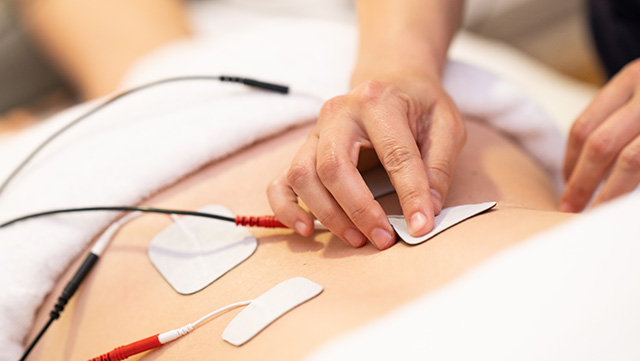 Ein Physiotherapeut wendet eine Elektrostimulation an.