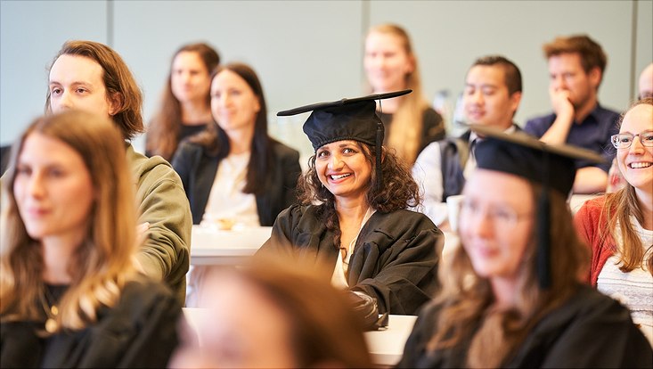 Auf diesem Bild sieht man einige sitzende Teilnehmer beim Vortrag zur Promoviertenfeier