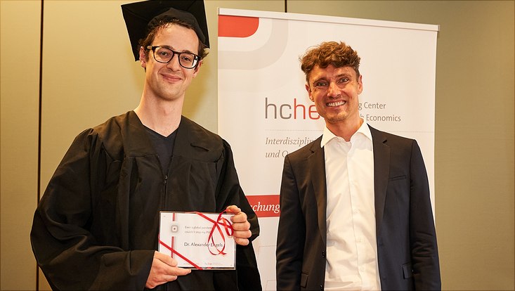 Auf diesem Bild sieht man Dr. Alexander Engels mit seinem Abschlussgeschenk und Prof. Dr. Jonas Schreyögg