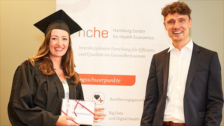 Auf diesem Bild sieht man Dr. Veronika Golubinski mit ihrem Abschlussgeschenk und Prof. Dr. Jonas Schreyögg