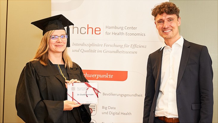 Auf diesem Bild sieht man Dr. Claudia Konnopka mit ihrem Abschlussgeschenk und Prof. Dr. Jonas Schreyögg