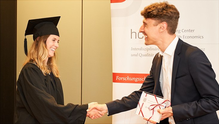 Auf diesem Bild sieht man wie sich Dr. Hannah König und Prof. Dr. Jonas Schreyögg die Hände schütteln