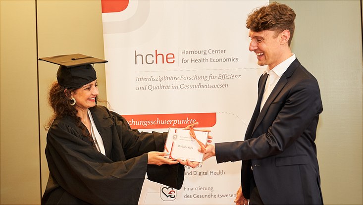 Auf diesem Bild sieht man Dr. Rucha Vadia mit ihrem Abschlussgeschenk und Prof. Dr. Jonas Schreyögg