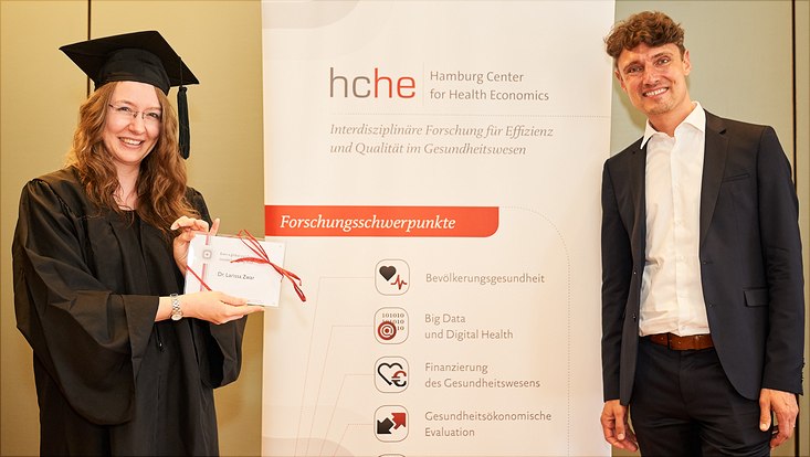 Auf diesem Bild sieht man Dr. Larissa Zwar mit ihrem Abschlussgeschenk und Prof. Dr. Jonas Schreyögg