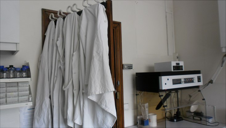 weiße Kittel, die an einer Tür in einem Labor hängen