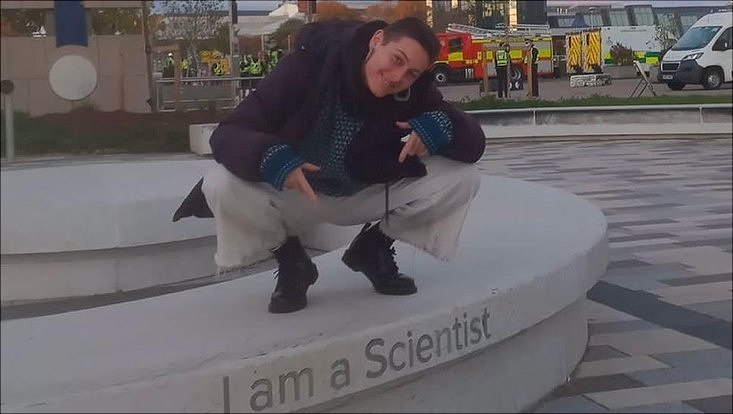 Photo of master graduate Ella Karnik Hinks above a lettering saying "I am a scientist"