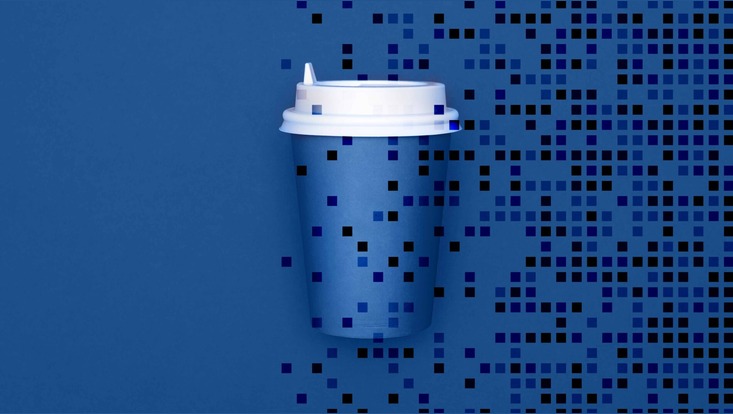 Einheitlich blauer Hintergrund. Davor ist ein dunkelblauer Pappbecher mit einem weißen Plastikdeckel zu sehen.