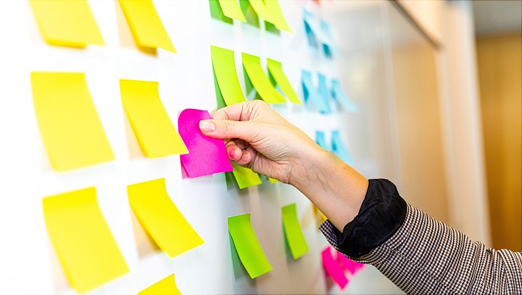 Eine Seminarteilnehmerin klebt Post-its an ein Whiteboard