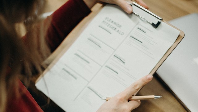 Lebenslauf auf Klemmbrett in der Hand einer Person