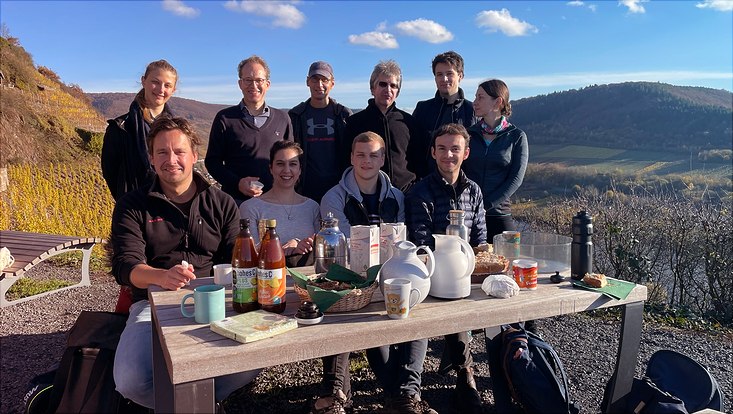 Das Projektteam des FNG-Siegels um Timo Busch sitzt zum Picknick an einem Tisch mit Weinbergen und der Mosel im Hintergrund.