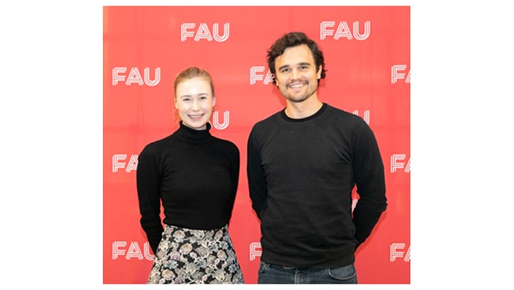 Lisa Scheitza und Raphael Tietmeyer vor einem Banner der FAU