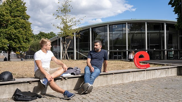 zwei Männer unterhalten sich vor dem Audimax
