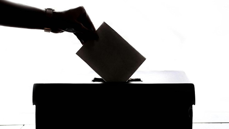 hand, die einen wahlzettel in eine wahlurne legt