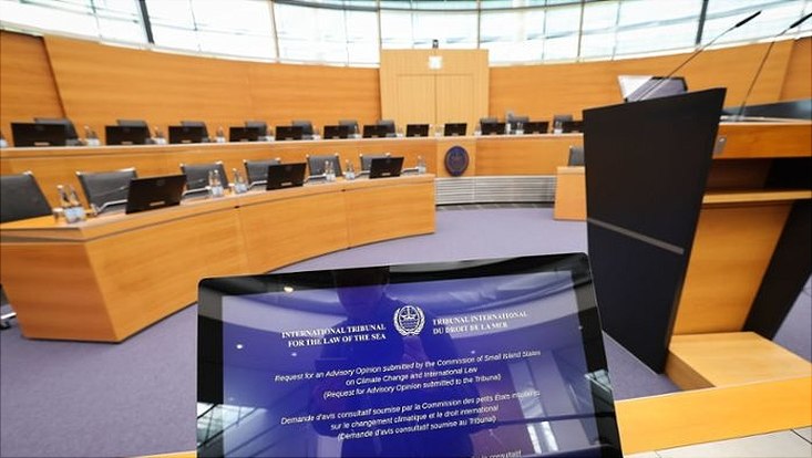 Bildschirm mit UN-Logo vor einem Plenarssal
