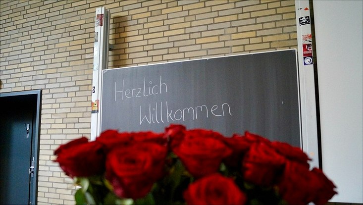 Im Vordergrund Rosen, im Hintergrund "Herzlich Willkommen"