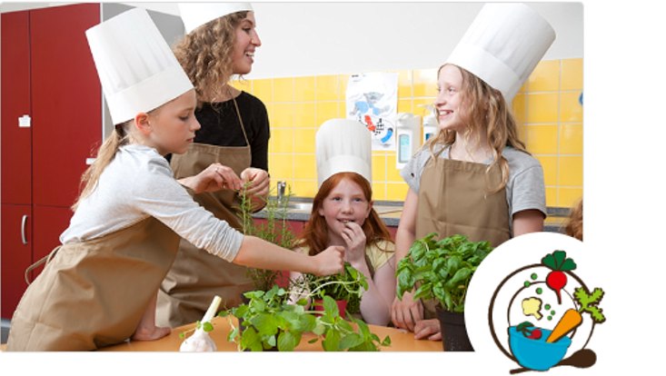 drei Mädchen und eine Frau stehen in der Küche und kochen