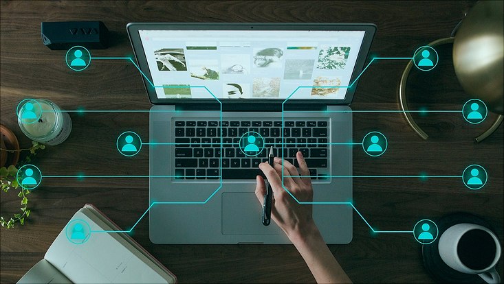 Laptop auf dem eine Hand liegt und Personensymbole davon abgehen