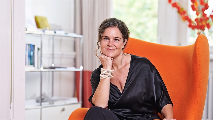 Frau die lächelnd auf einem Sofa sitzt.