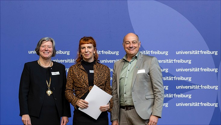 Foto der Preisverleihung mit Anna Fünfgeld in der Mitte. Sie hält die Preisurkunde.