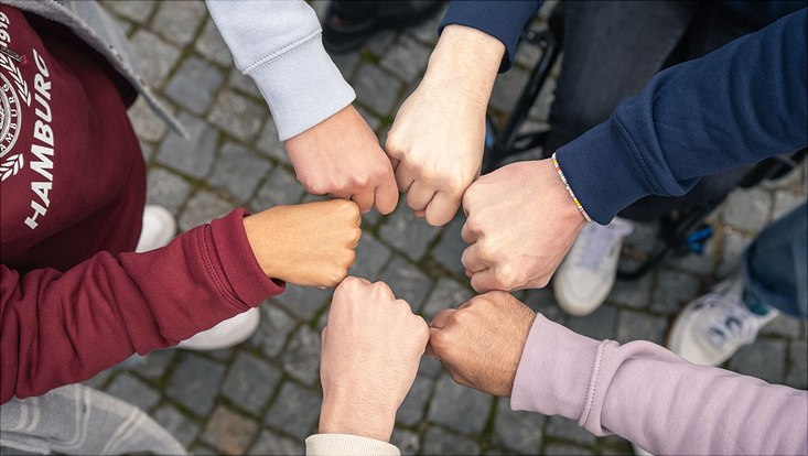 Hände von Studierenden, die in der Mitte zusammenkommen