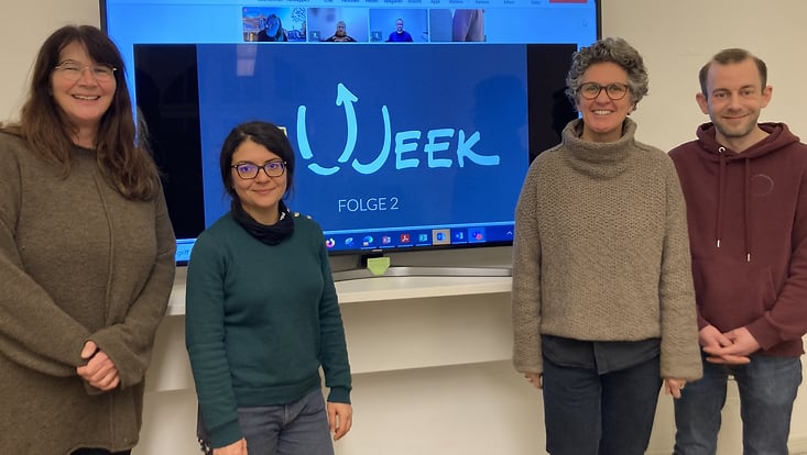 Gruppe The Week 2024, Personen vor einem Bildschirm mit virtuellen Teilnehmenden