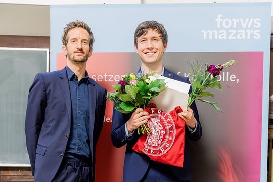 Zwei Personen vor einem Banner