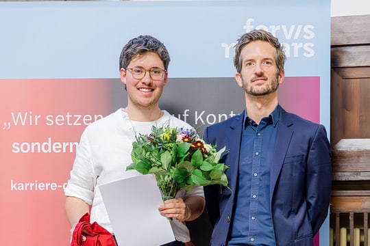 Zwei Personen vor einem Banner