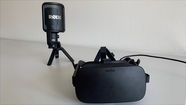 Auf einem Tisch steht ein Mikrofon. Davor liegt eine schwarze VR-Brille.